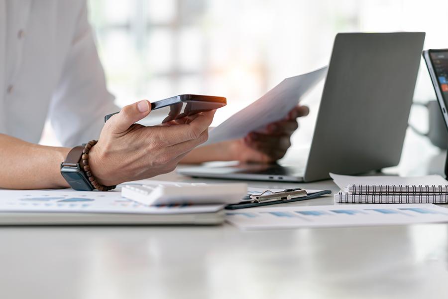 Person holding phone in front of computer